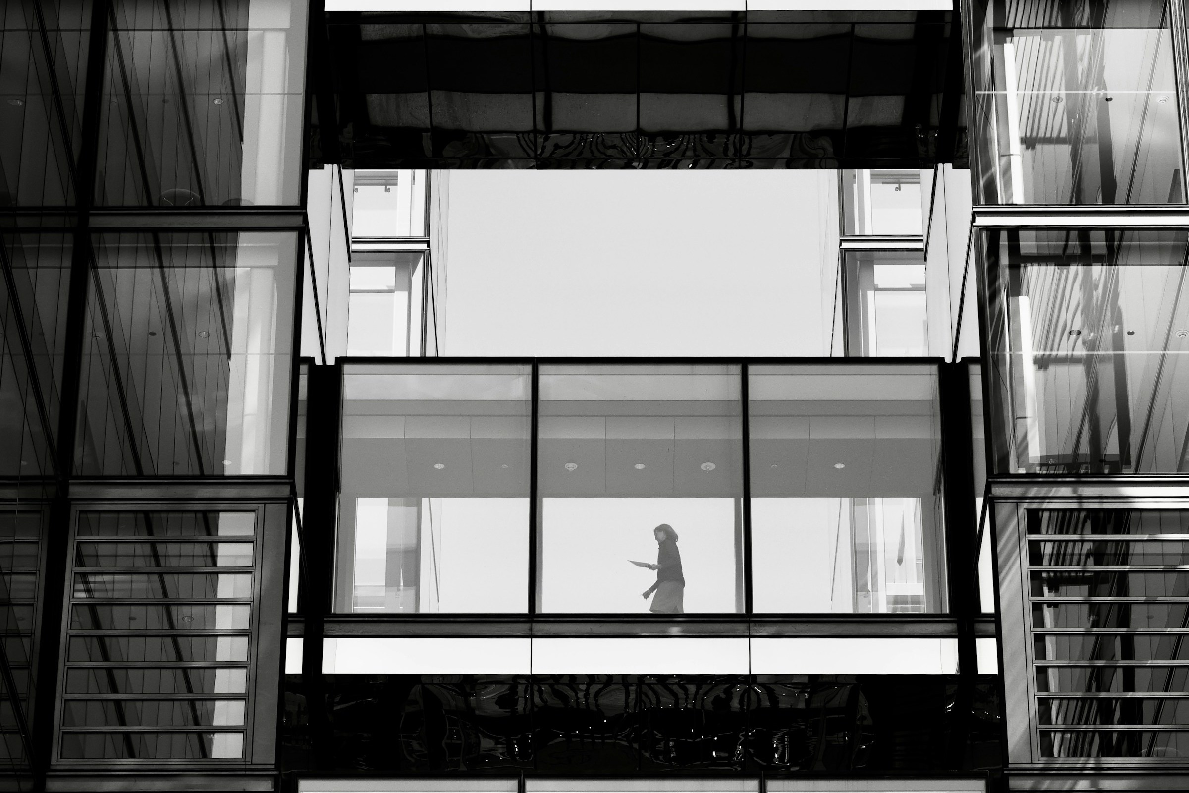 Une femme traverse une passerelle au sein d’une architecture contemporaine
